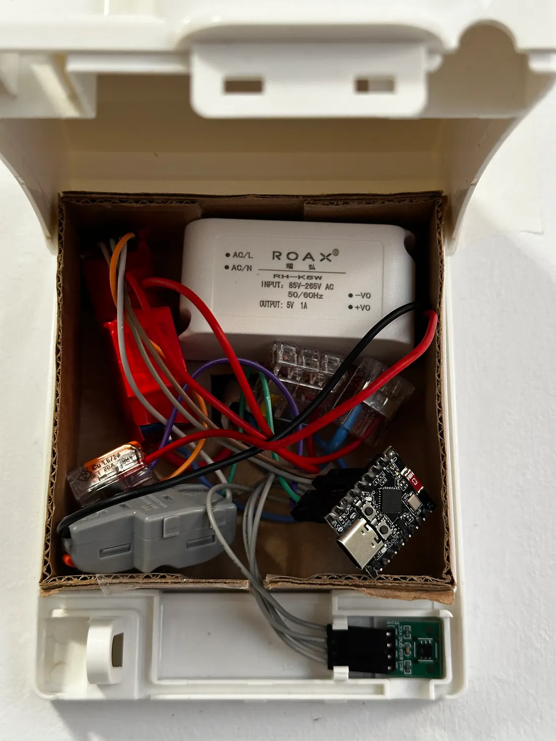 A mains-powered ESP32-based smart thermostat installed on the wall